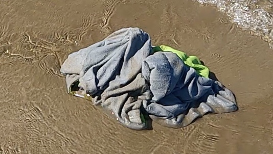 A wet sandy towel on the beach
