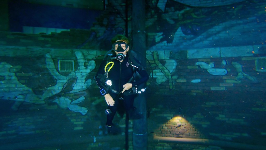 A scuba woman in front of a grafitti wall Deep Dive Dubai