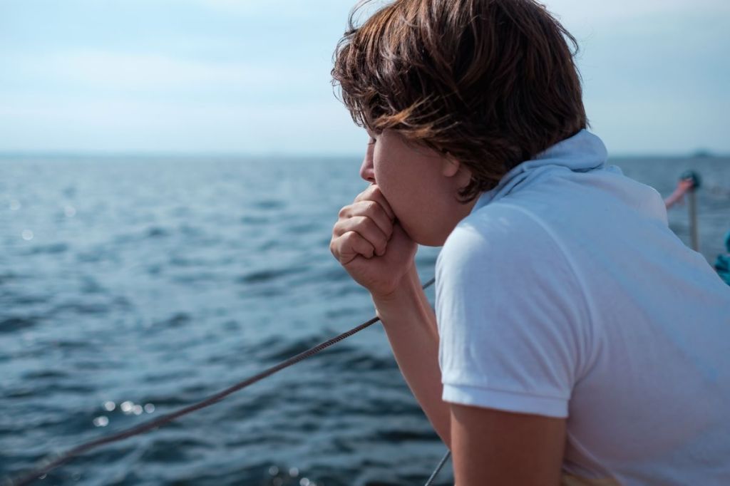 Woman leaning over boat feeling seasick